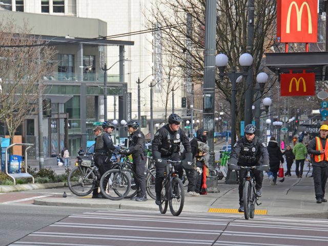 Seattle Police Department officers on bikes bike in front of the McDonald's at Third Avenue and Pine Street in downtown Seattle.