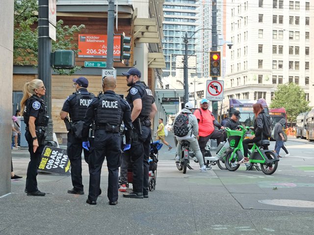Seattle Police Department officers stand at an intersection near Third Avenue and Pine Street in downtown Seattle.
