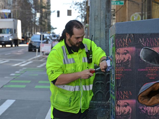 Downtown ambassador removing posters and graffiti.